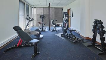 A gym with various exercise equipment including a bench, elliptical, and weight machines.