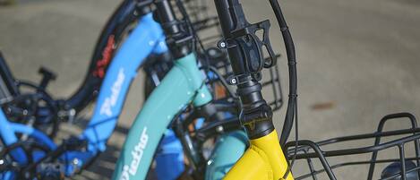 A row of bicycles with a yellow and teal color scheme, equipped with baskets and fenders.