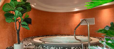 A spa area with a circular hot tub, a shower, and a tiled floor.