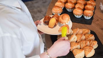 Une personne qui sert des pâtisseries, les prenant sur un plateau pour les déposer dans une assiette.