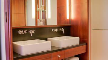 A bathroom with two sinks, a large mirror, and wooden shelving with towels.