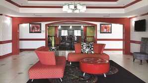 A spacious living area with a red and white color scheme, featuring a sofa set, a coffee table, and a television mounted on the wall.