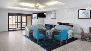 A modern living room with a sofa set, two armchairs, a coffee table, and a TV. - La Quinta Inn & Suites by Wyndham Woodward (Woodward)