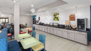 A modern kitchen with a central island, seating area with colorful chairs, and a refrigerator. - La Quinta Inn & Suites by Wyndham Woodward (Woodward)