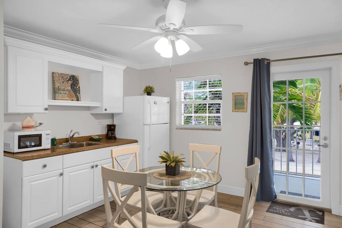 A kitchen with white cabinets, a microwave, a sink, and a ceiling fan.
