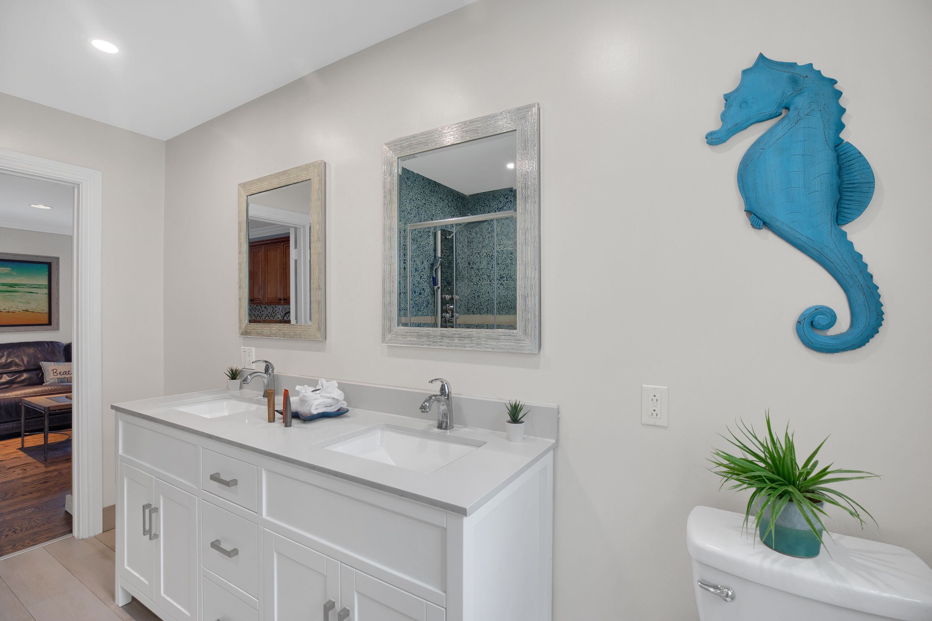 Une salle de bain avec deux lavabos, un grand miroir et une décoration représentant un hippocampe.