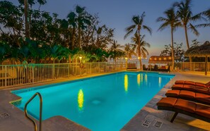 A swimming pool with a 5 ft depth marker, surrounded by palm trees and lounge chairs. - Atlantic Bay Resort (Tavernier)