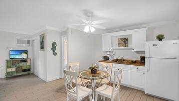 A modern kitchen with white cabinets, a round glass table, and white chairs.