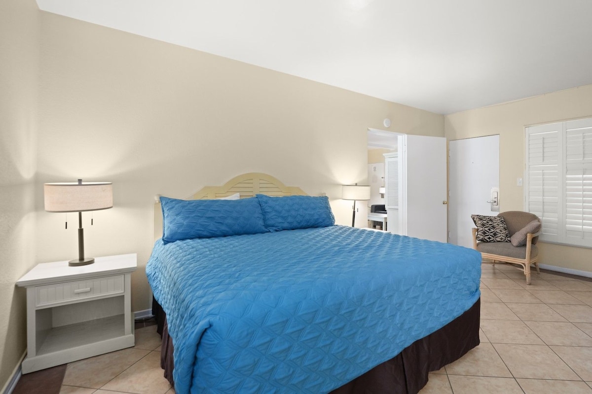 A bedroom with a bed, bedside tables, a chair, and a window with shutters.