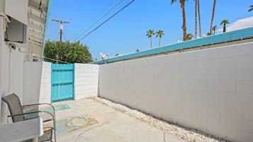 A courtyard with a blue gate, a concrete wall, and a white building with a satellite dish.