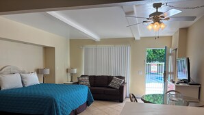 Ein Hotelzimmer mit Bett, Sofa, Schreibtisch und Deckenventilator.