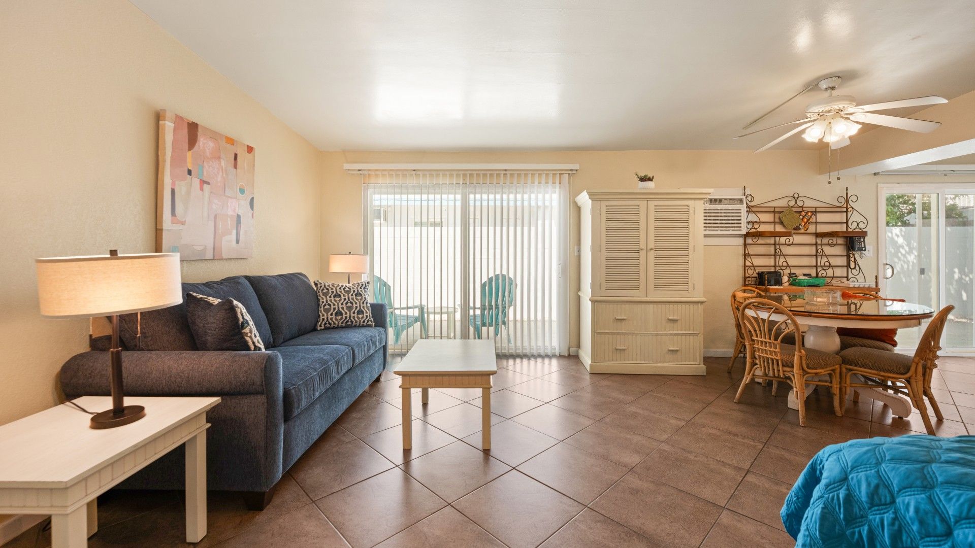 A living room with a sofa, a coffee table, a dining area with a table and chairs, and a ceiling fan.