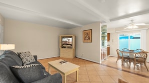A living room with a sofa, a television, a coffee table, and a dining area with chairs and a table. - The Villas of Palm Springs by CoolVacay (Palm Springs)