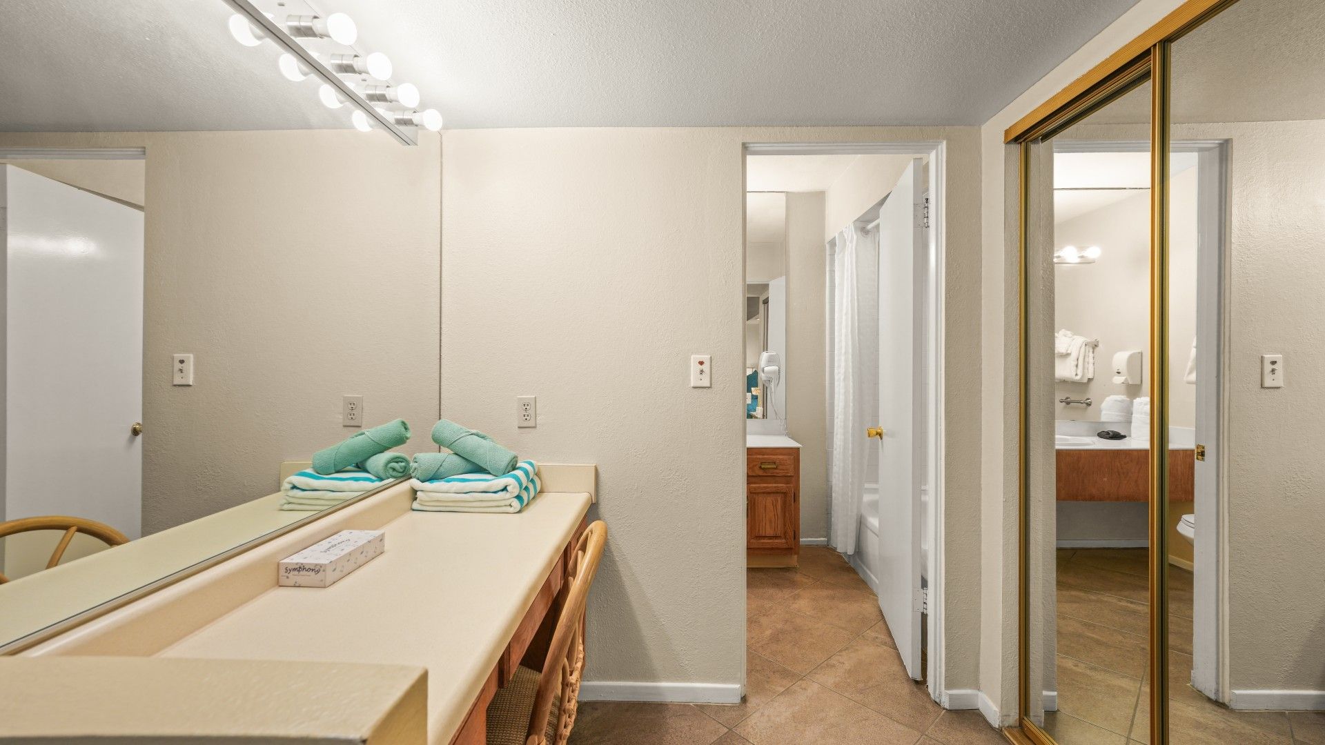 A bathroom with a large mirror, a vanity with a countertop, and a towel rack.