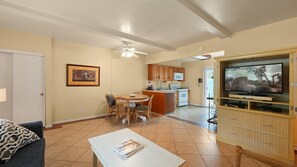 A living room with a television, a dining area with a table and chairs, and a kitchen with wooden cabinets and a microwave. - The Villas of Palm Springs by CoolVacay (Palm Springs)
