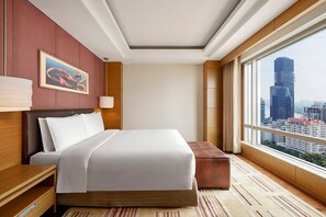 A hotel room with a large bed, a wooden nightstand, a desk, a window with a city view, and a painting on the wall. - InterContinental Saigon, an IHG Hotel (Ho Chi Minh City)