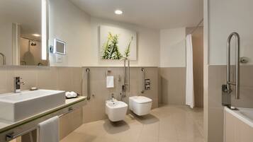 Een moderne badkamer met een groot wastafel, toilet, douche en bidet.