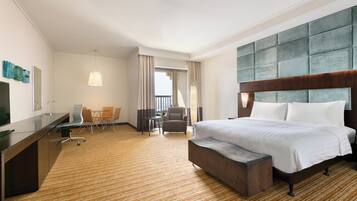 A hotel room with a large bed, a desk, a chair, and a small table.
