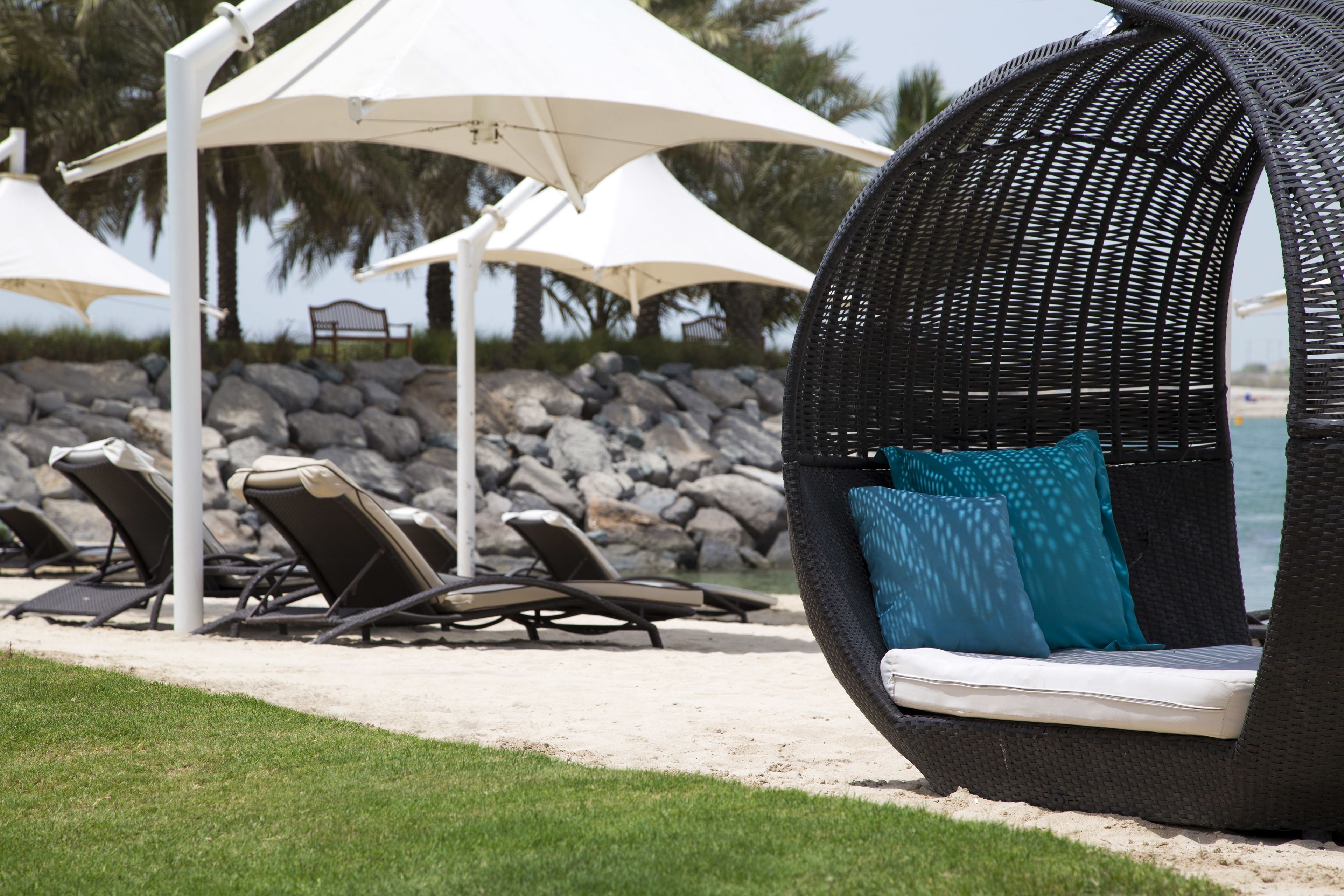 A beachside lounge area with wicker chairs and white umbrellas.
