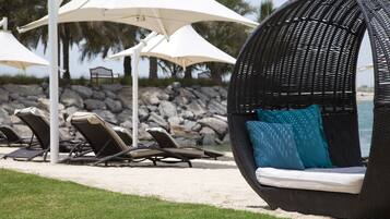 A beachside lounge area with wicker chairs and white umbrellas.
