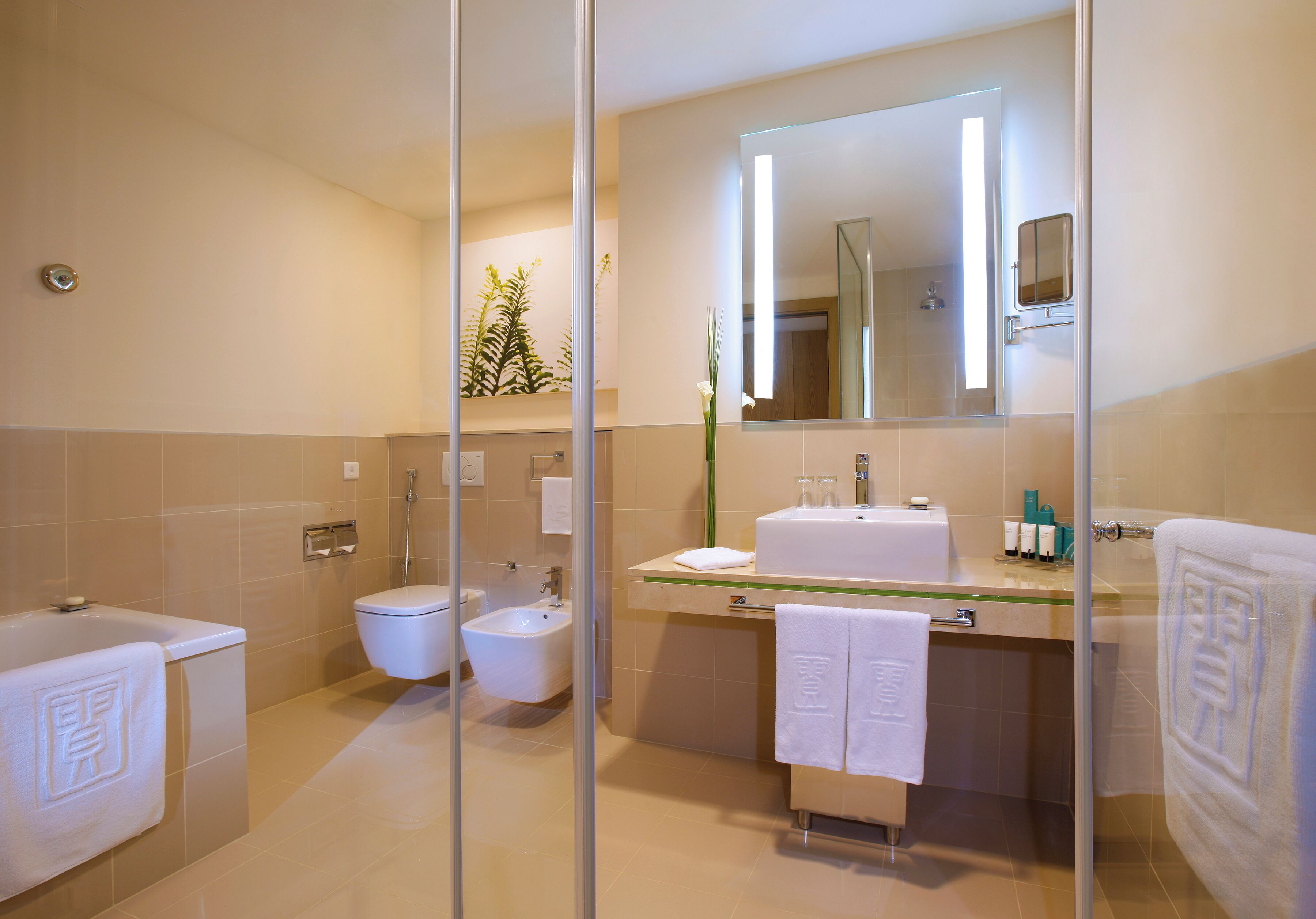 Un baño moderno con cabina de ducha de vidrio, un bidé, una bañera y un espejo grande sobre el lavabo.