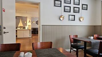 A restaurant interior with wooden tables, chairs, and a wall adorned with framed pictures.