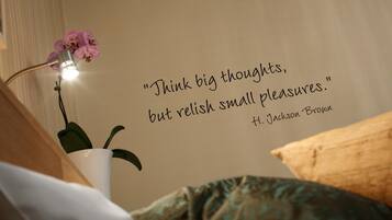 A wall with a quote by H. Jackson Brown, a bedside lamp, and a potted orchid.