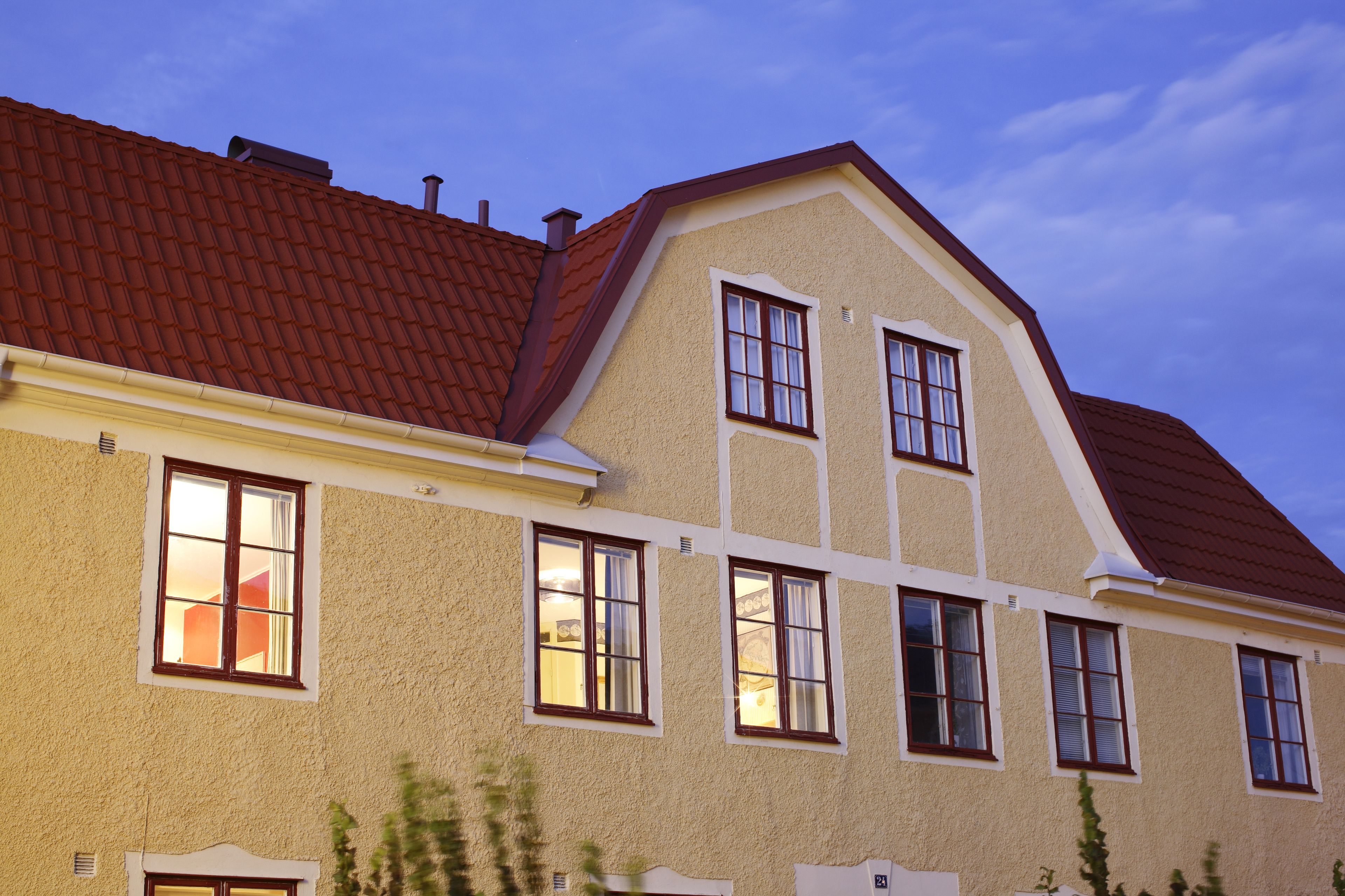 A two-story building with a red-tiled roof, multiple windows, and a beige facade.