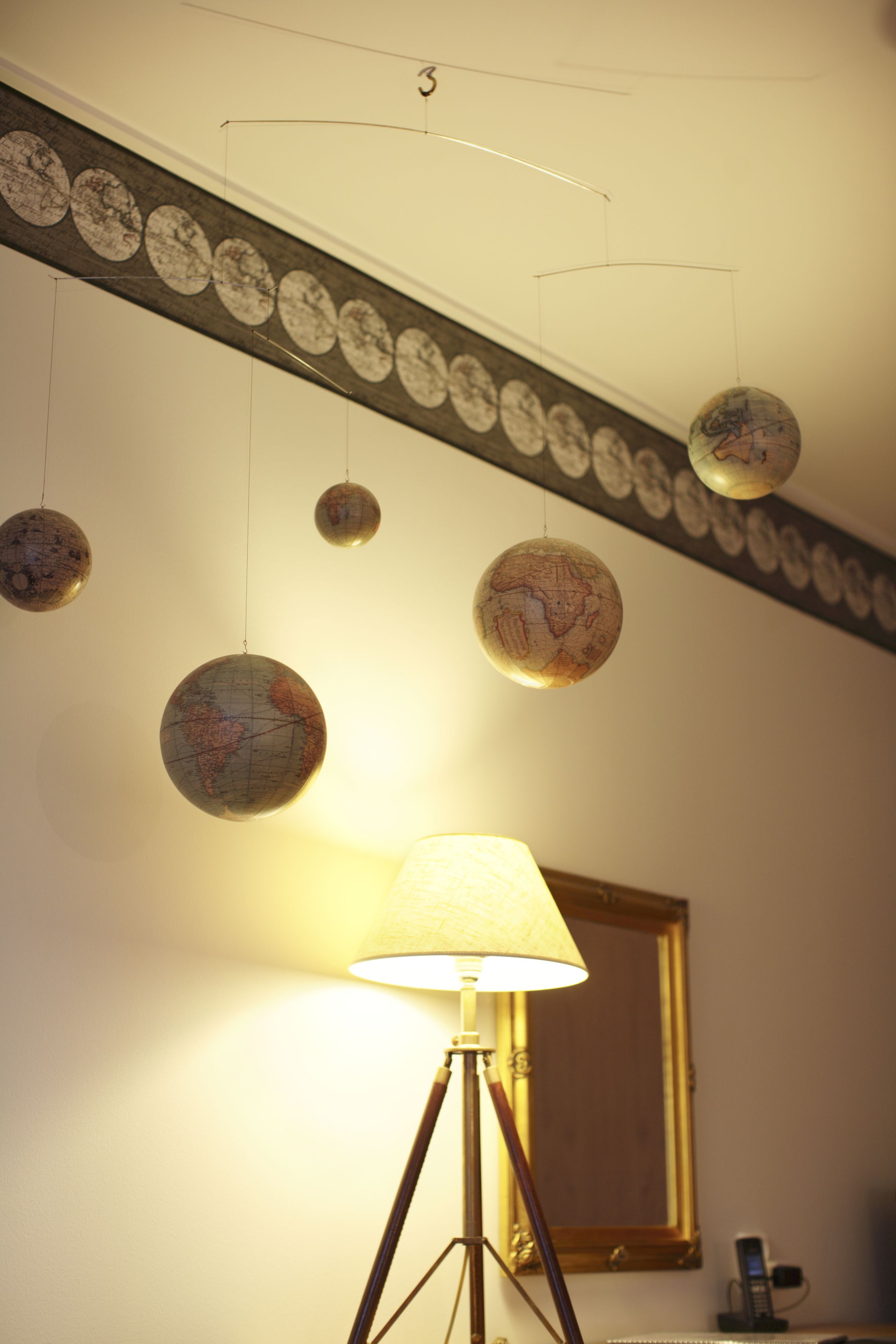 A room with a globe-themed light fixture, a floor lamp, and a mirror on the wall.