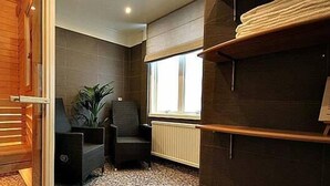 A bathroom with a wooden door, a radiator, a potted plant, and a window.