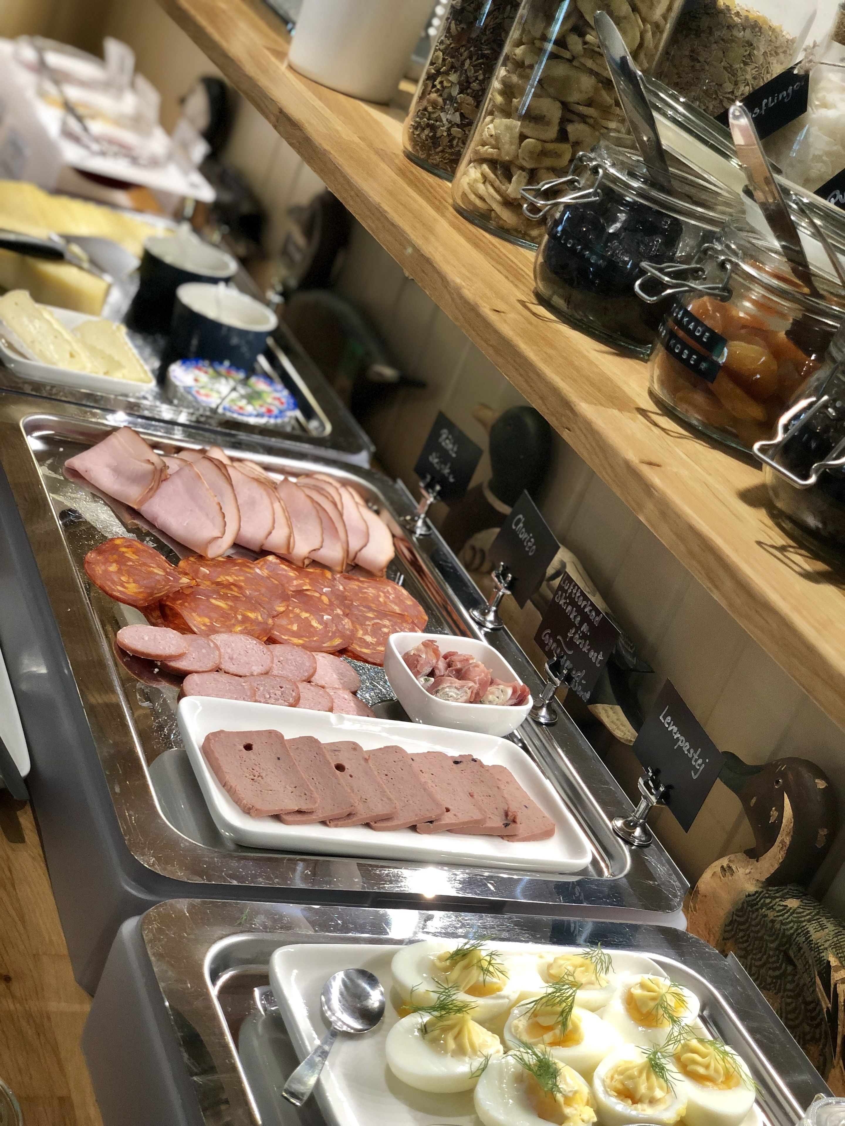 A buffet with various food items including sliced meats, cheeses, and a selection of pickles.