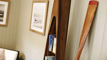 A bookshelf with books and a wooden paddle leaning against a wall.