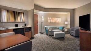 A hotel room with a kitchenette, a sofa, a TV, and a large abstract painting on the wall. - Courtyard by Marriott Dallas Allen at Allen Event Center (Allen)