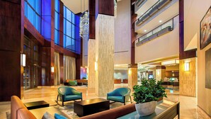 A spacious lobby with modern furnishings, a large central column, and a view of the upper floors. - Courtyard by Marriott Dallas Allen at Allen Event Center (Allen)