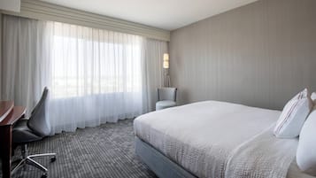 Une chambre d’hôtel avec un grand lit, un bureau, une chaise et une lampe.