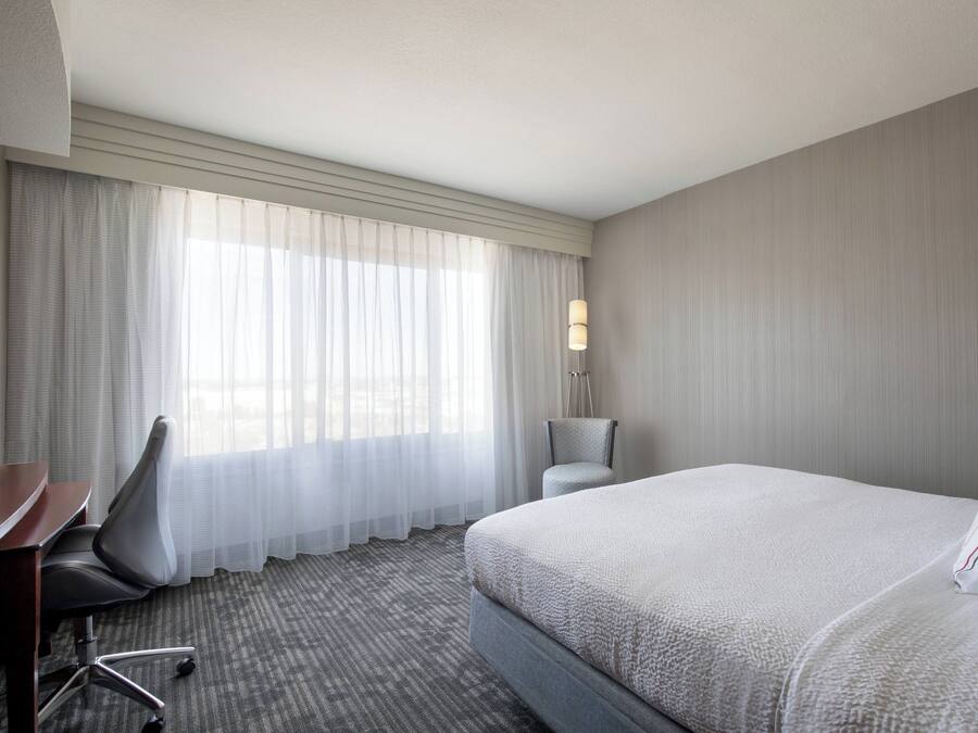 Une chambre d’hôtel avec un grand lit, un bureau, une chaise et une lampe.