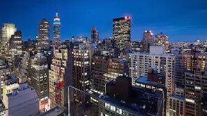 Eine städtische Skyline im Abenddämmerung mit beleuchteten Gebäuden und klarem Himmel.