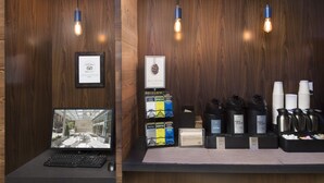 Ein Empfangsschalter mit einem Laptop, gerahmten Zertifikaten und Kaffeemaschinen sowie Teeausgabespendern mit Branding.