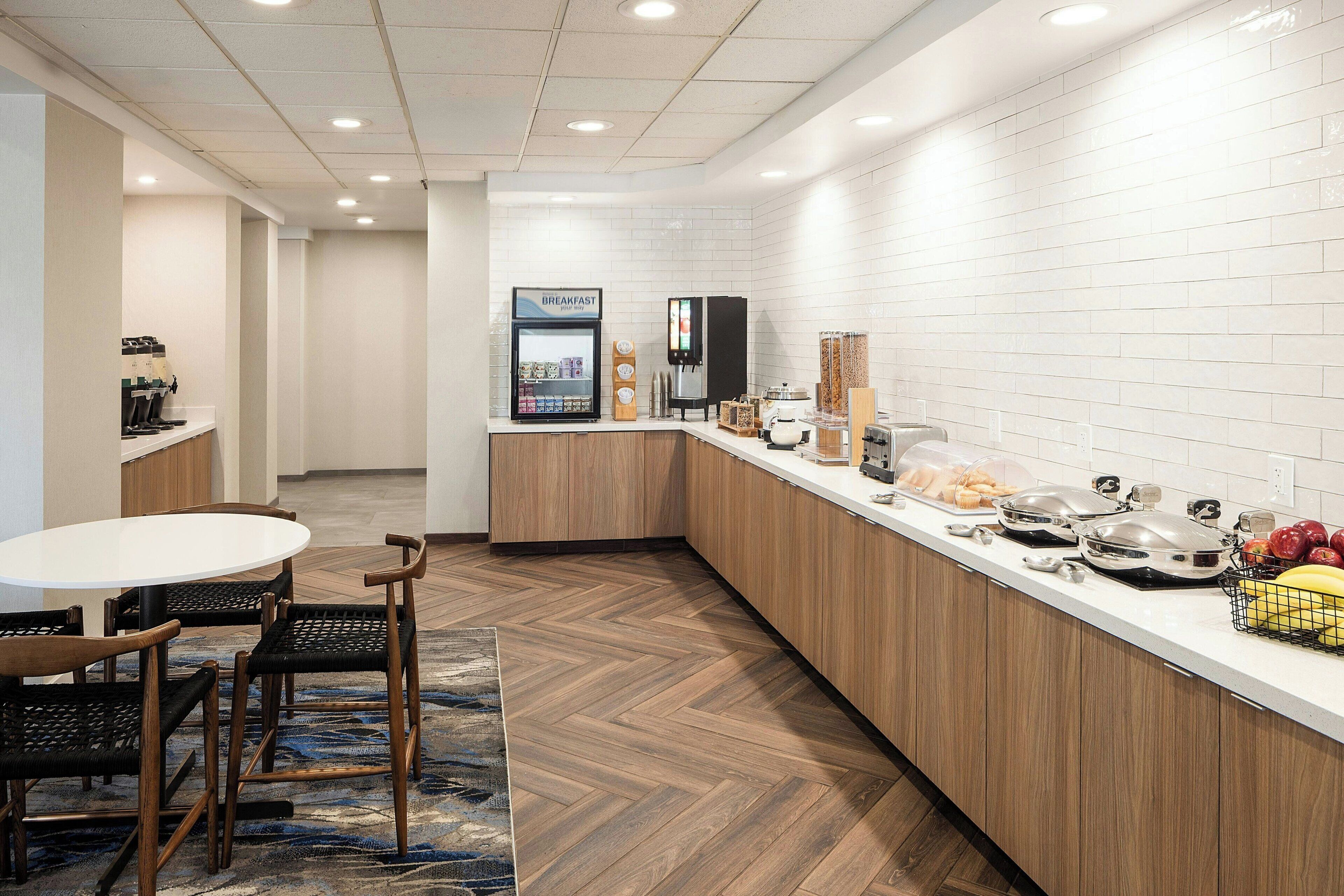 A modern kitchen with a breakfast bar, coffee machine, and a fruit basket.