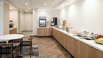 A modern kitchen with a breakfast bar, coffee machine, and a fruit basket.