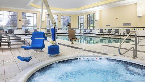 Een zwembadgedeelte met een jacuzzi, ligbedden en een toezichthoudersstoel.