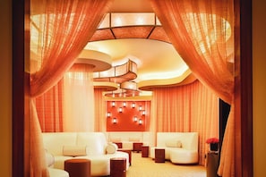 A modern lounge area with a curved ceiling, plush seating, and a decorative wall panel.