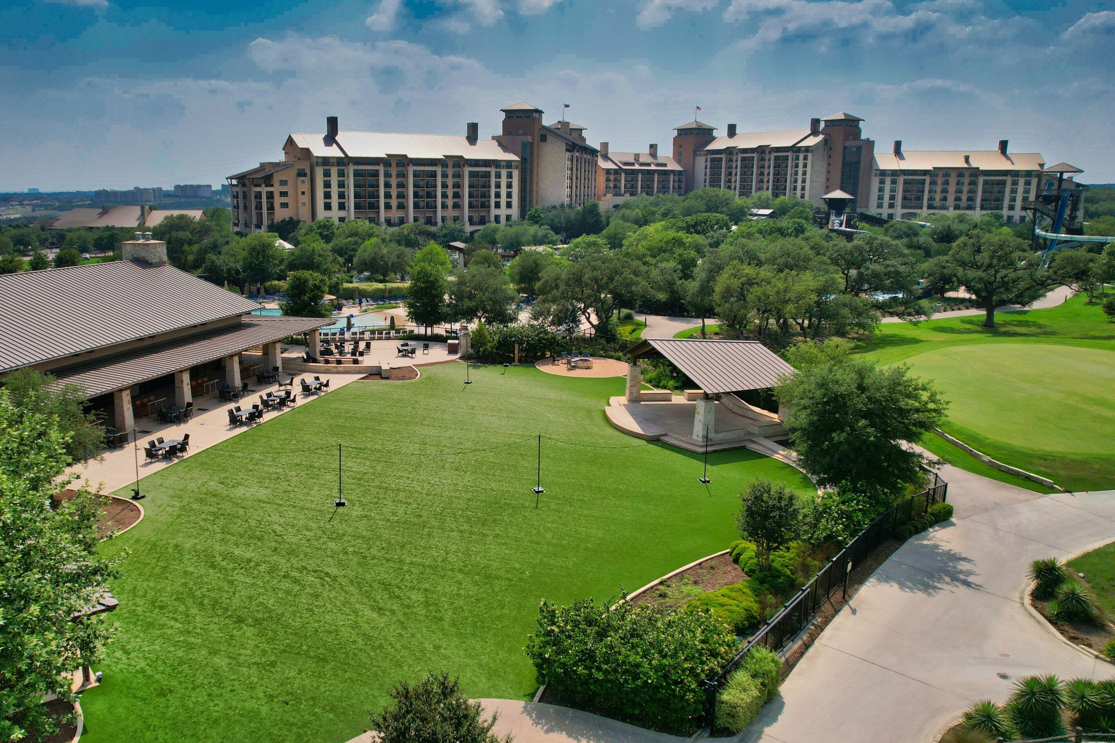 A large hotel with multiple buildings, a well-maintained lawn, and outdoor seating areas.