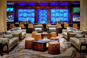 A bar area with multiple seating options, including sofas and armchairs, and a bar counter with shelves of bottles.