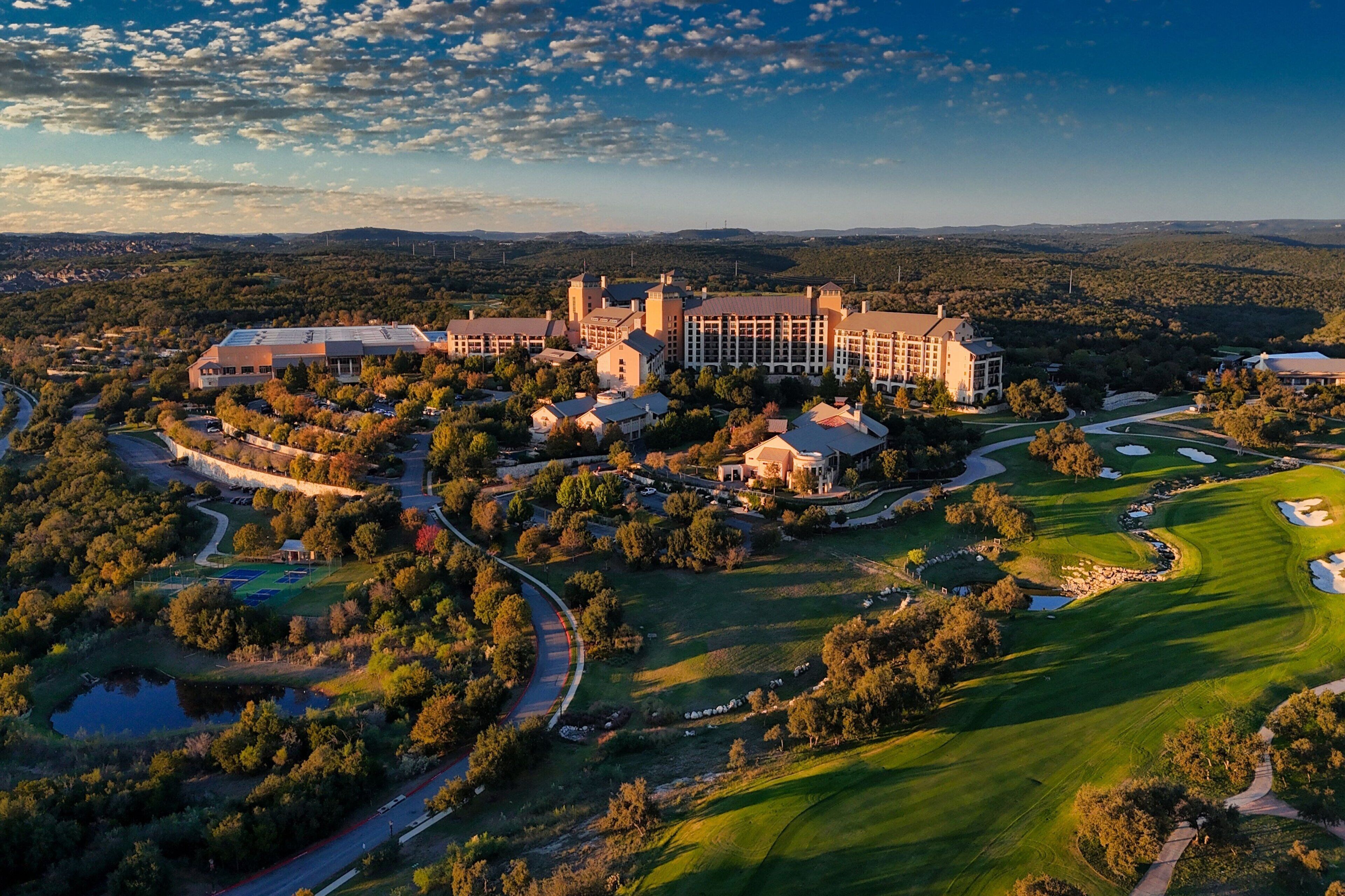 A large resort with multiple buildings, a golf course, and surrounding wooded areas.
