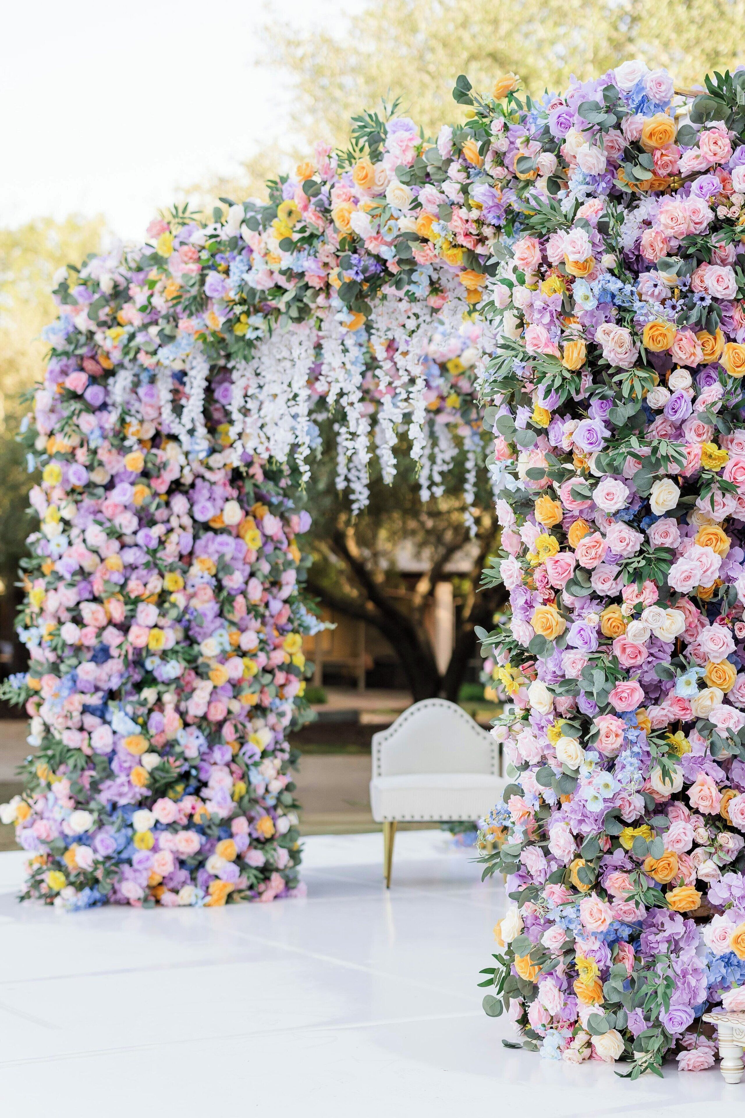 Une arche ornée de fleurs, avec un banc blanc en arrière-plan.