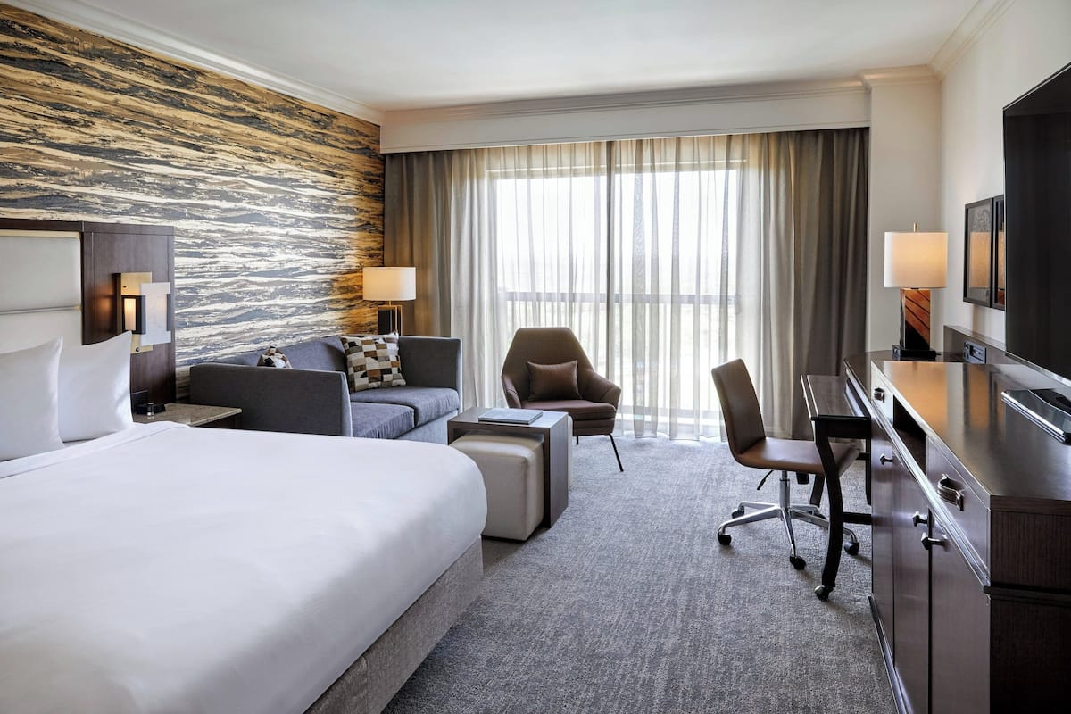 Una habitación de hotel con una cama grande, un escritorio, una silla, un sofá y un televisor.