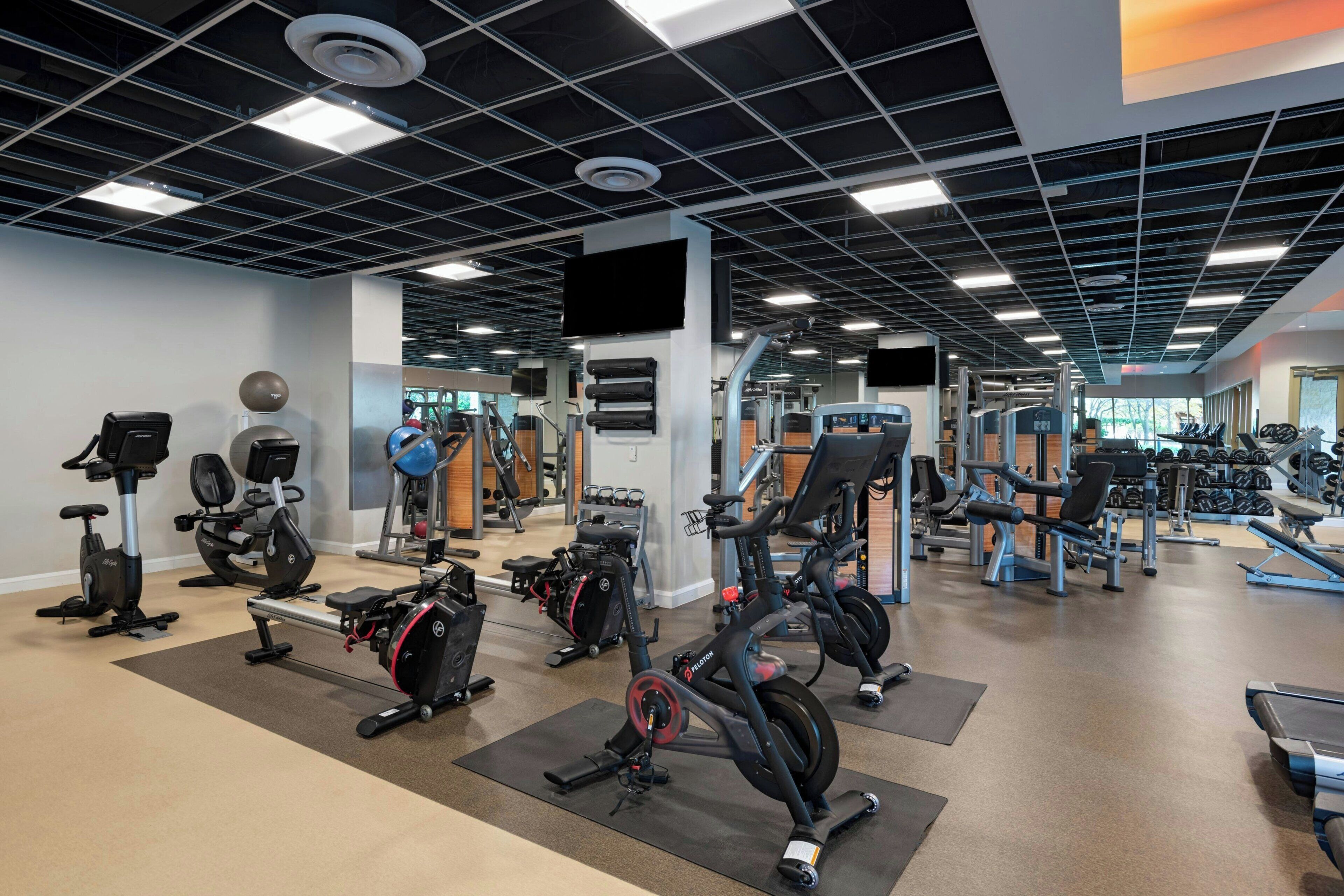 Une salle de sport équipée de divers appareils d’exercice, notamment des tapis de course, des vélos d’appartement et des appareils de musculation.