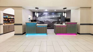 Un área de recepción con un cartel que dice "Fort Worth Stock Yards" y una vitrina de comida a la izquierda.