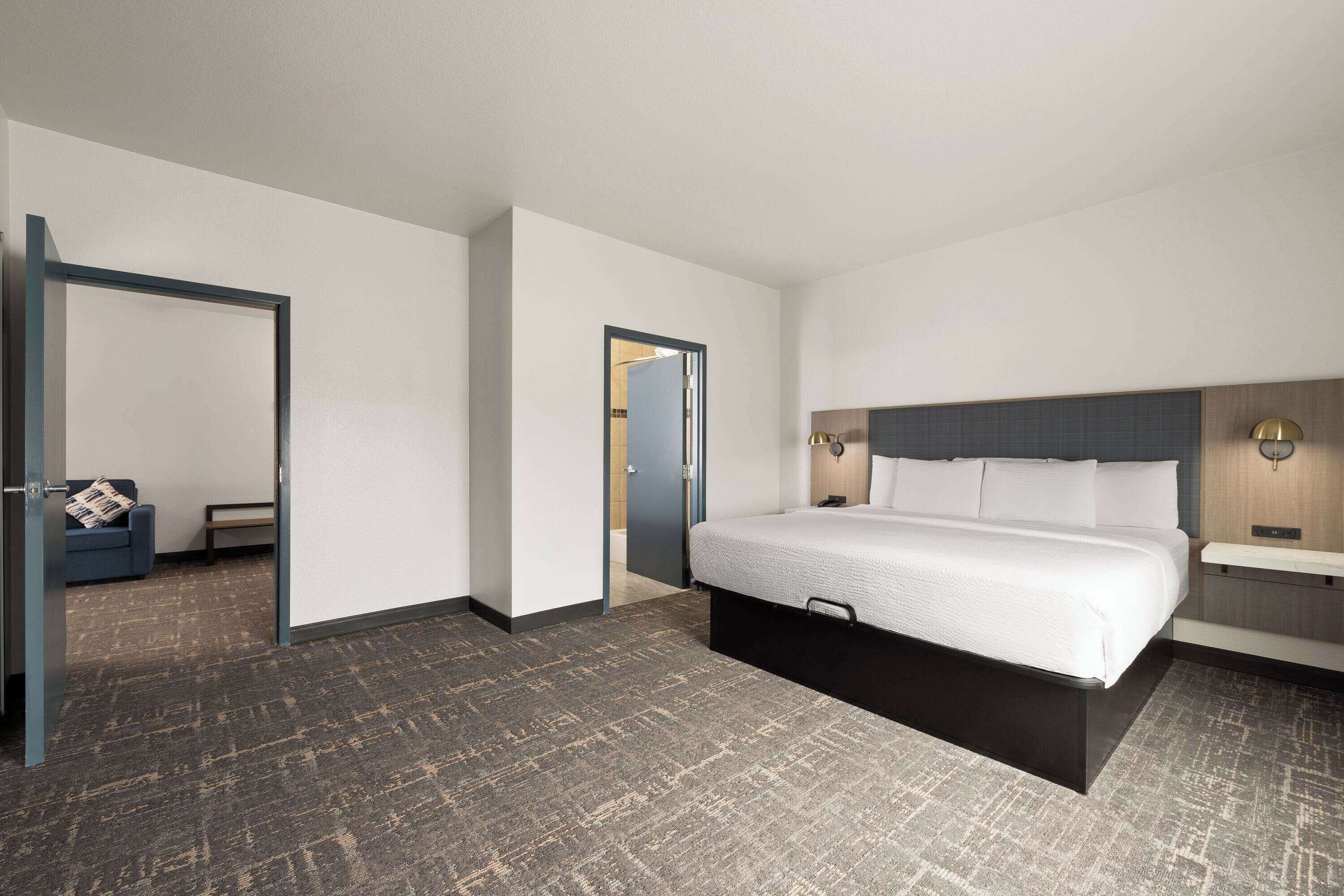 Une chambre d’hôtel avec un lit, une table de chevet et une salle de bain équipée d’un lavabo.
